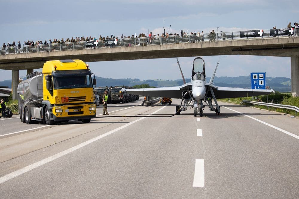 Ein Betankungsfahrzeug betankt einen F/A-18 unter einer Autobahnbrücke