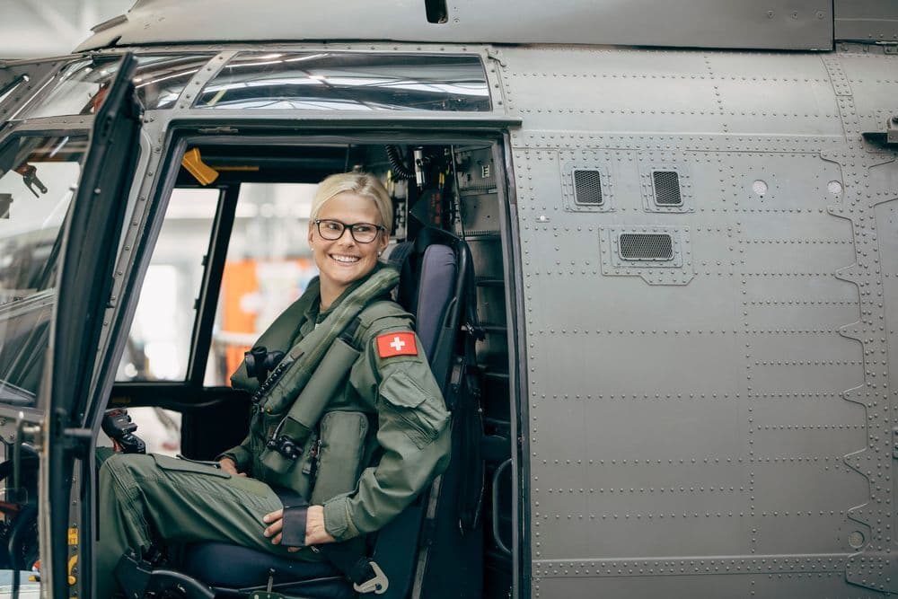 Eine Helikopterpilotin sitzt bei geöffneter Türe im Super Puma 