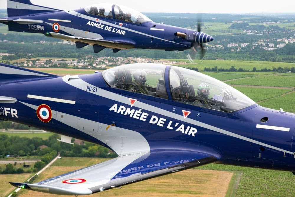 2 blaue PC-21 der Aremee de l'air fliegen nebeneinander über Felder 