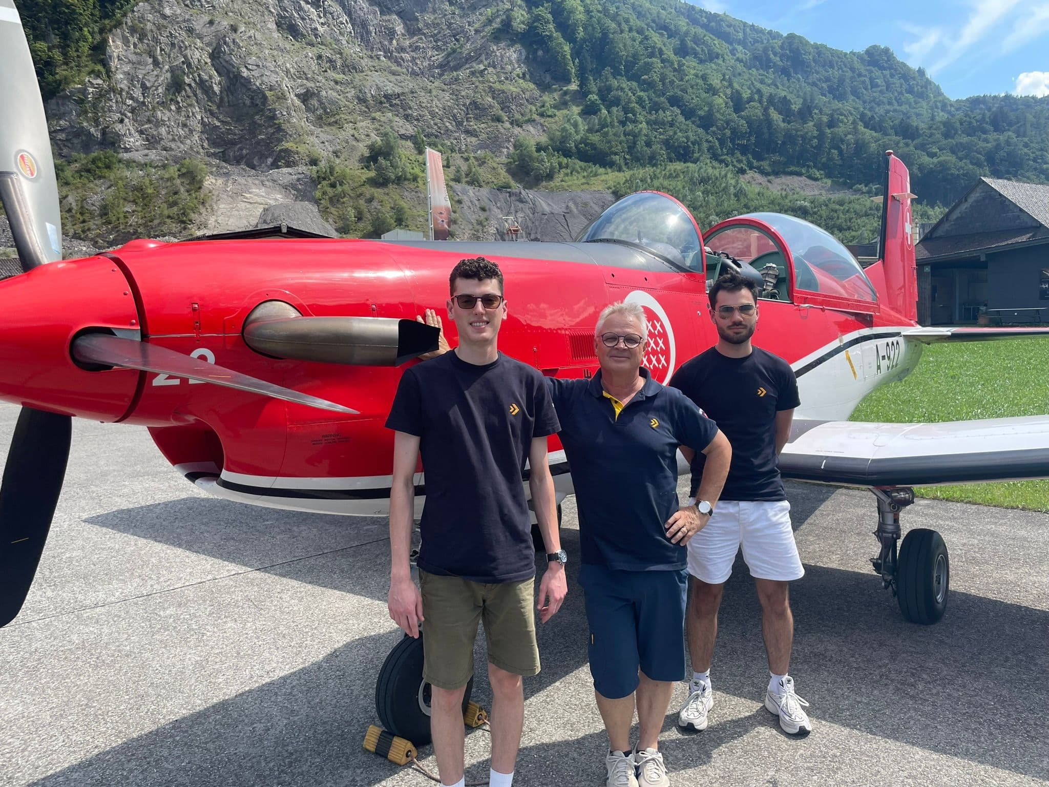 Zwei SPHAIR Teilnehmer und 1 SPHAIR Fluglehrer stehen vor einem roten PC-7