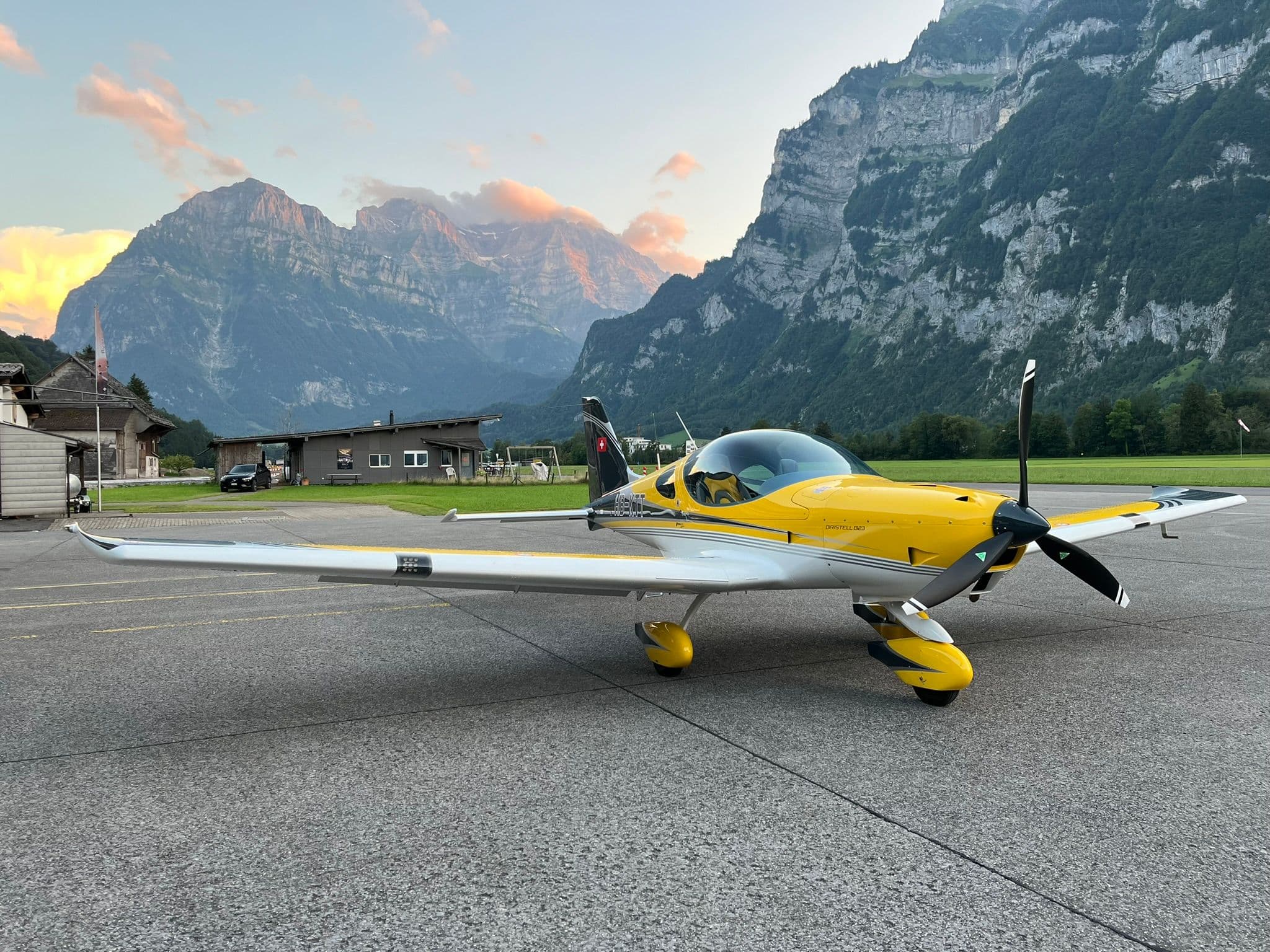 Ein Flugzeug steht bei Sonnenuntergang auf dem Rollfeld auf dem Flugplatz Mollis.